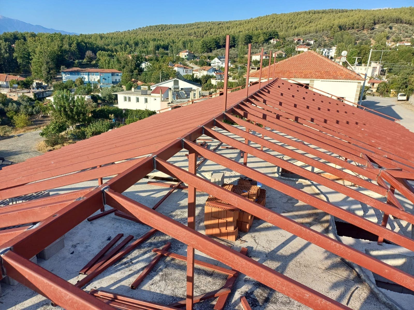 Eğimli çatıda kırmızı oksit boyalı çelik çatkı elemanları